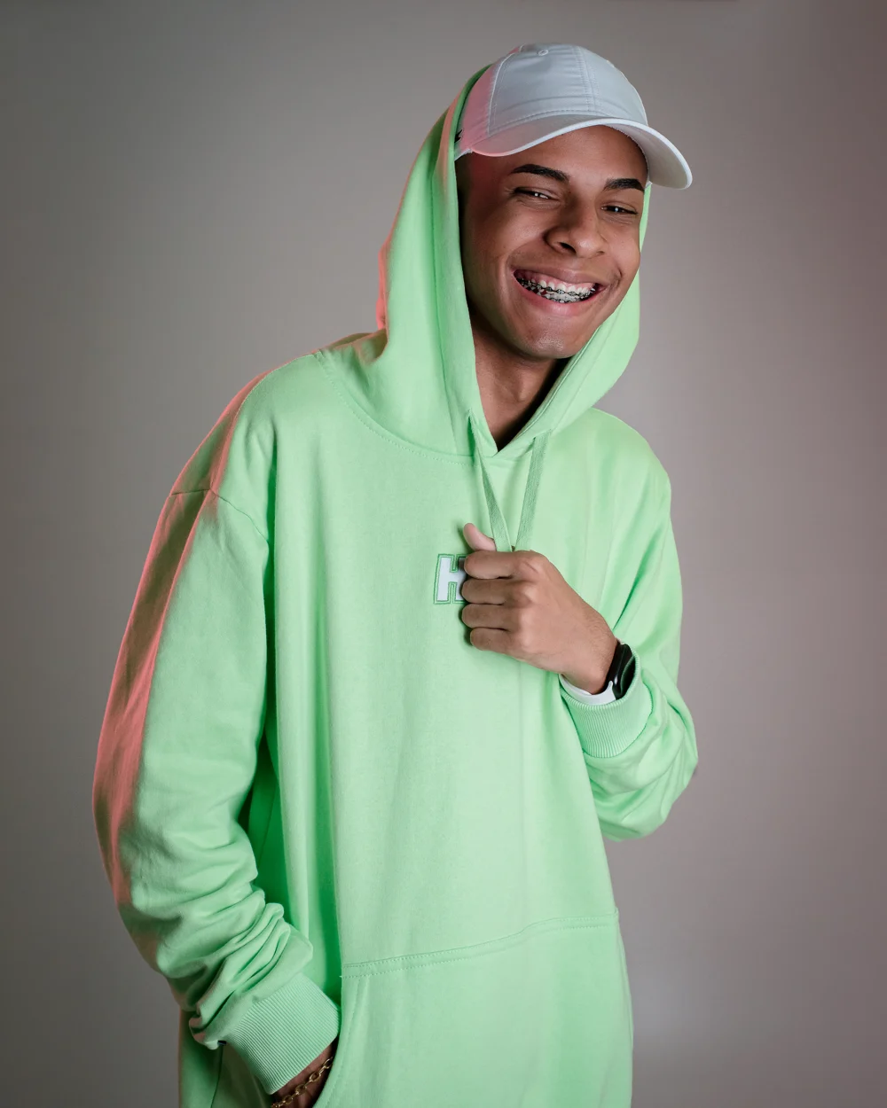 DJ Felipe Único, de moletom verde, em retrato de estúdio
